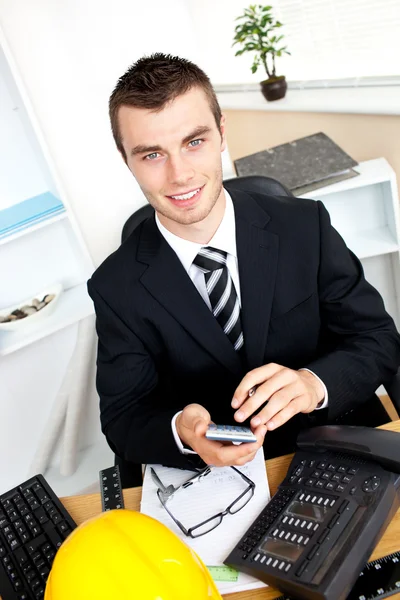 Positive businessman using his calculator looking at the camera — Stock Photo, Image