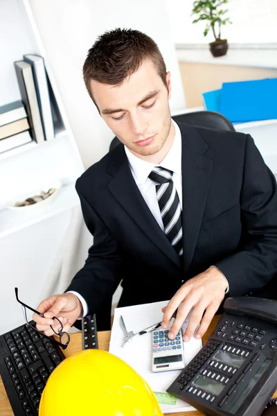 Серьезный молодой бизнесмен с помощью калькулятора — стоковое фото
