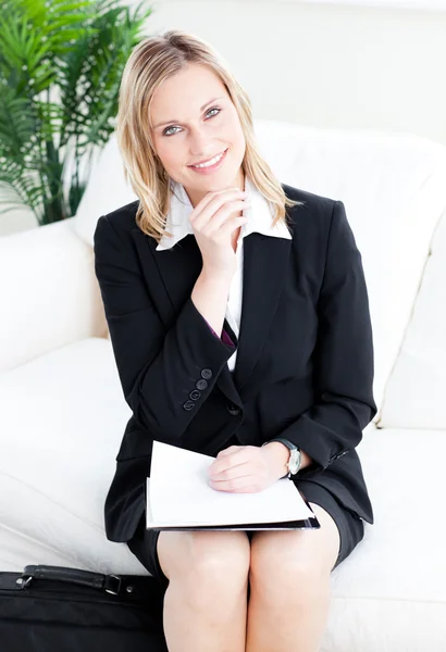 Mujer de negocios brillante sonriendo a la cámara sentada en un sofá — Foto de Stock
