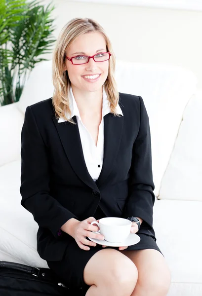 Captivating caucasian businesswoman holding a cup sitting on a s — Stock Photo, Image