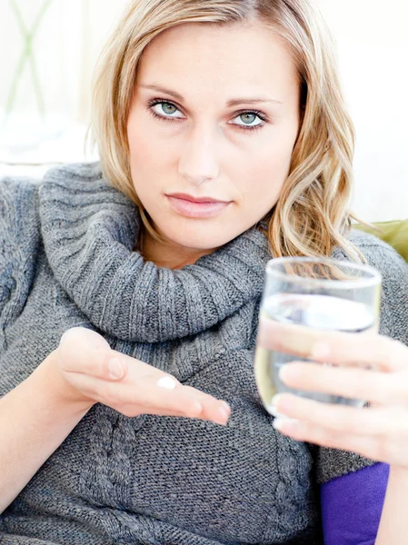 Sick depressed woman holding pills and water looking at the came — Stock Photo, Image