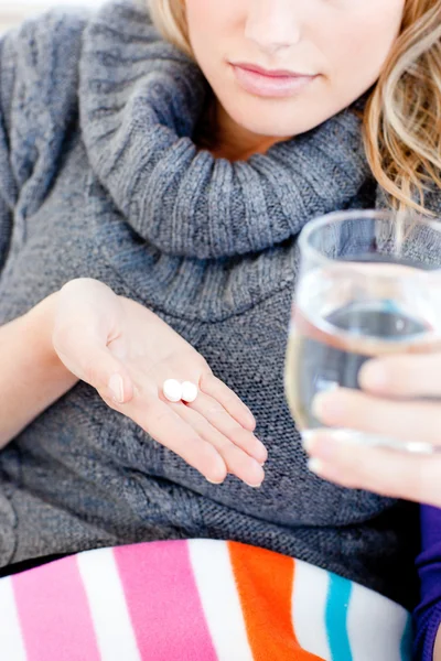 Close-up de uma mulher doente segurando pílulas e água — Fotografia de Stock