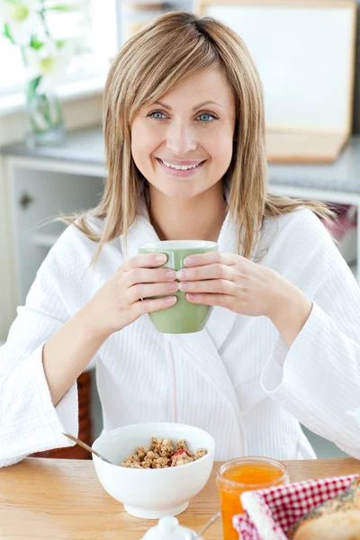 Hermosa mujer sosteniendo una taza de café comiendo cereales en el ki —  Fotos de Stock