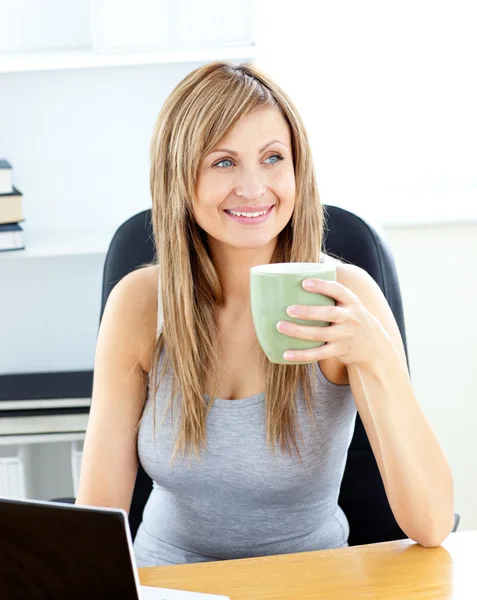 Femme d'affaires rayonnante tenant une tasse en utilisant son ordinateur portable — Photo