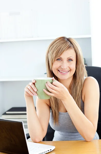 Attraktiva affärskvinna innehar en kopp med sin laptop — Stockfoto