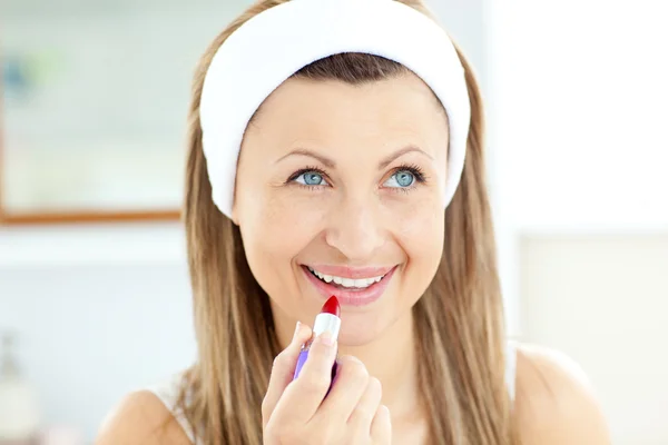 Mooie jonge vrouw met behulp van een rode lippenstift in de badkamer — Stockfoto