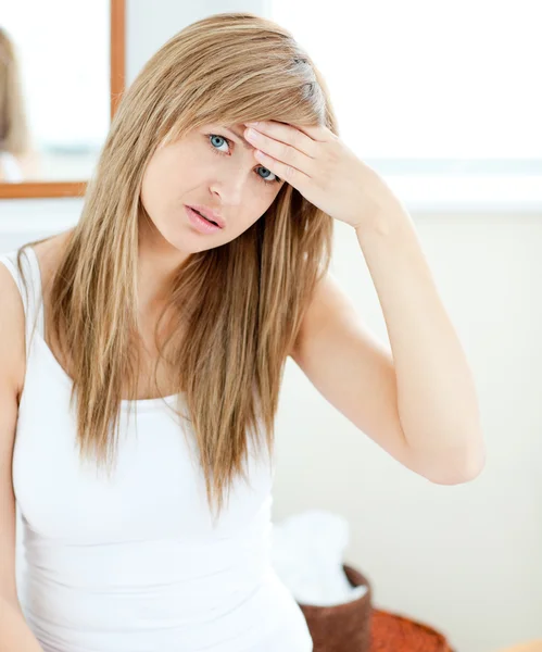 Depressed woman with a headache looking at the camera — Stock Photo, Image