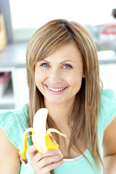 Sonriendo joven sosteniendo un plátano mirando a la cámara —  Fotos de Stock