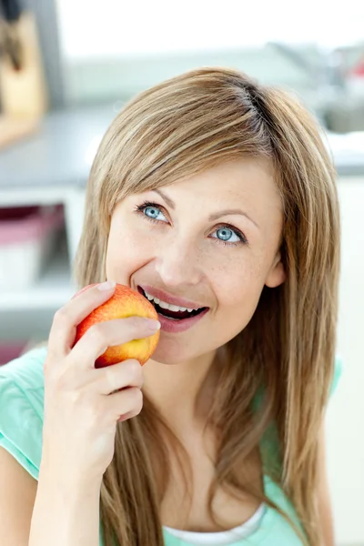 Захоплююча біла жінка їсть яблуко на кухні — стокове фото