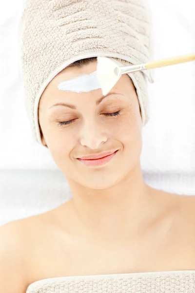 Mujer joven descansando recibiendo crema blanca en su cara —  Fotos de Stock