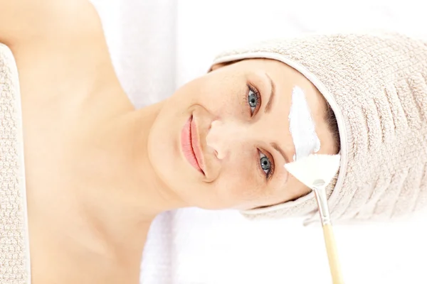 Pretty young woman receiving white cream on her face — Stock Photo, Image