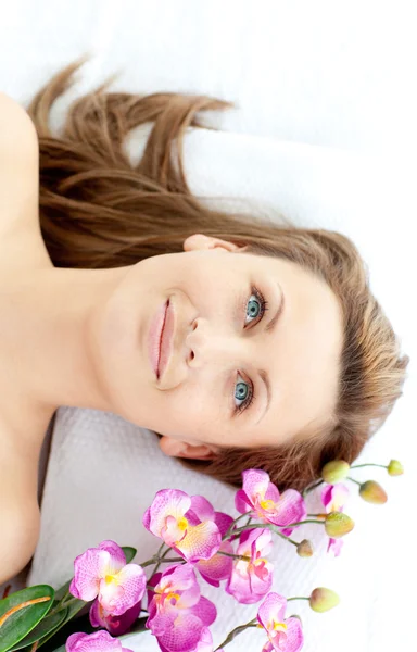 Affascinante giovane donna sdraiata su un tavolo da massaggio con fiori — Foto Stock