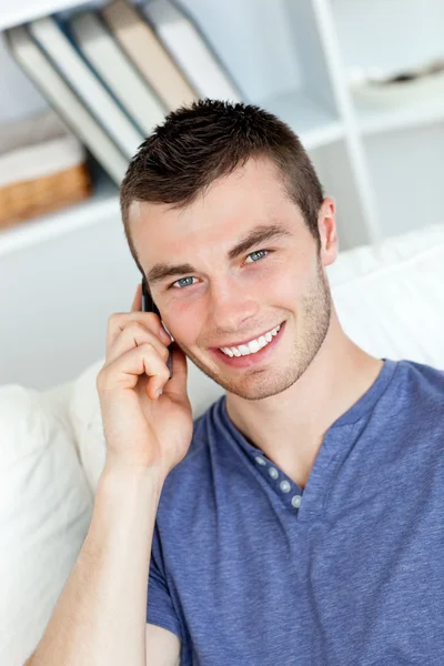 Χαρούμενος νεαρός άνδρας που μιλάει στο τηλέφωνο να χαμογελά στη φωτογραφική μηχανή — Φωτογραφία Αρχείου