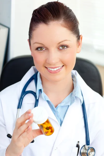 Gloeiende jonge vrouwelijke arts kijken naar pillen — Stockfoto