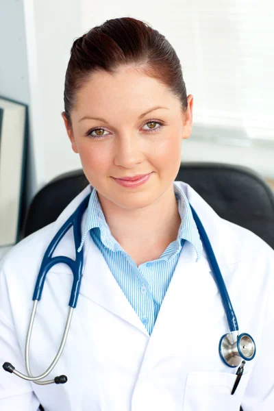 Pewna siebie kobieta lekarz uśmiecha się do kamery siedzi — Zdjęcie stockowe