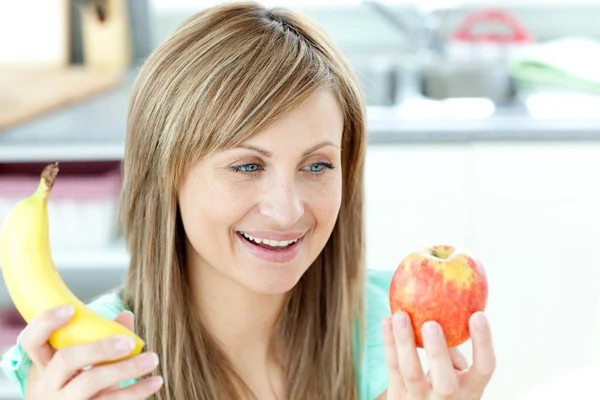 Jolly young woman holding an appke and a banana — Stock Photo, Image