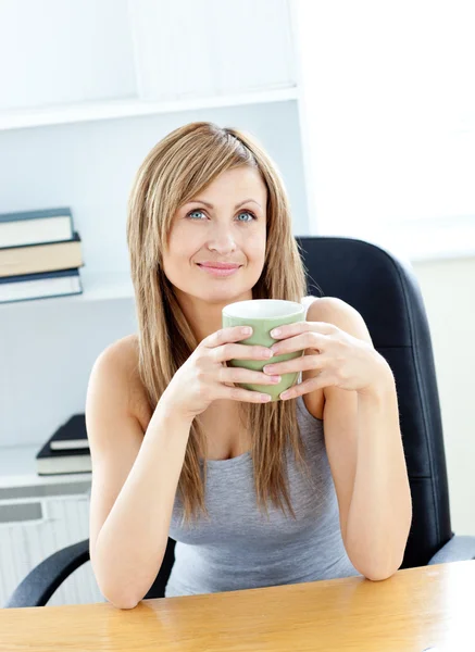Uvolněná žena drží pohár, sedí na židli doma — Stock fotografie