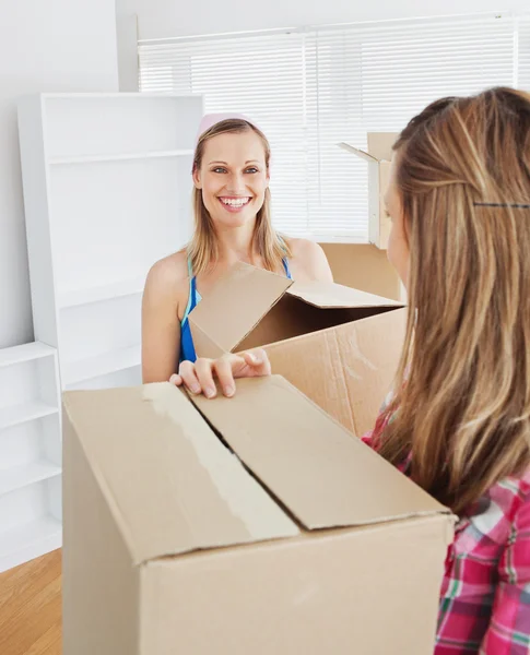 Two radiant female friends holding boxes after moving — Stock Photo, Image