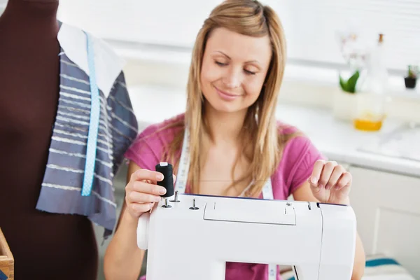 Heldere jonge vrouw met behulp van haar naaimachine — Stockfoto