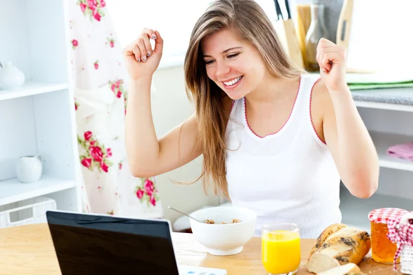 Mujer joven entusiasta mirando su computadora portátil con los brazos en alto —  Fotos de Stock