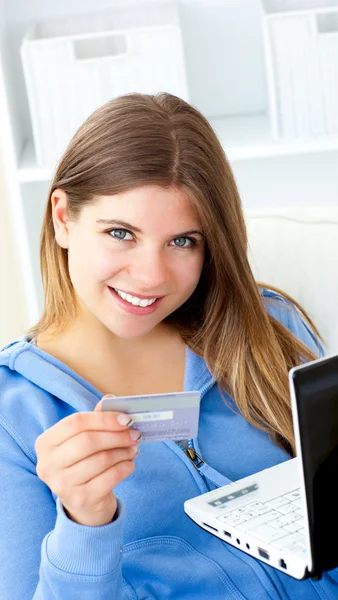 Retrato de una mujer bonita sosteniendo una tarjeta y un ordenador portátil mirando — Foto de Stock