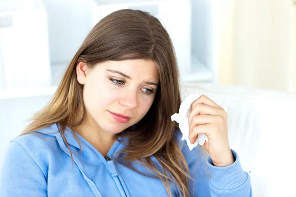 Smutny młoda kobieta trzyma tkanek, siedząc w pokoju dziennym — Zdjęcie stockowe