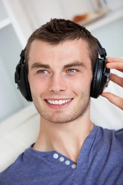Pohledný mladý muž poslouchá hudbu se sluchátky — Stock fotografie