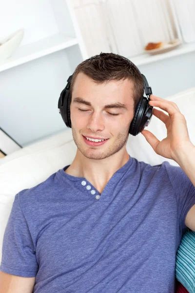 Avslappnad ung man lyssnar på musik med hörlurar — Stockfoto