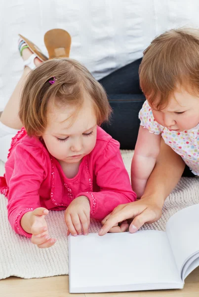 Bambini concentrati che leggono un libro con la madre — Foto Stock