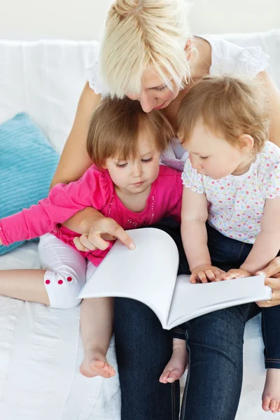 Famiglia luminosa che legge un libro sul divano — Foto Stock