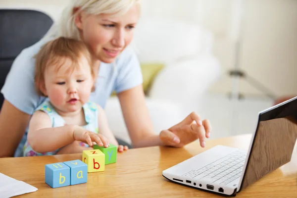 Famiglia positiva usando il computer portatile e giocando con i giocattoli — Foto Stock
