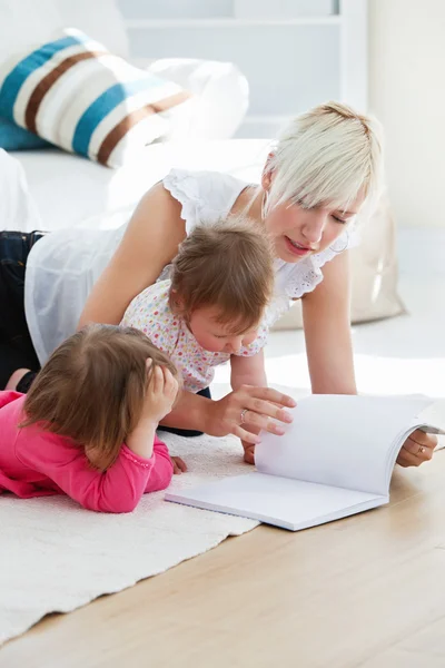 Lezen van een boek op de verdieping en gelukkige familie — Stockfoto