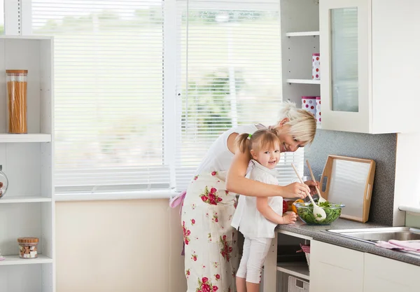 Jolly girl preparing a salad with her mother — Stock Photo, Image