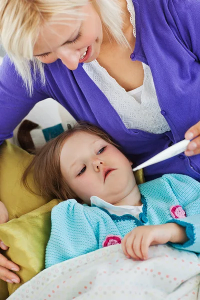 Attentive mother takes her daughter's temperature — Stock Photo, Image