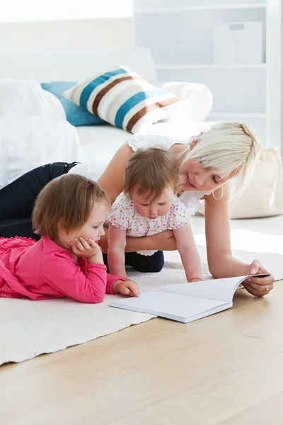 Giovane famiglia positiva che legge un libro sul pavimento — Foto Stock