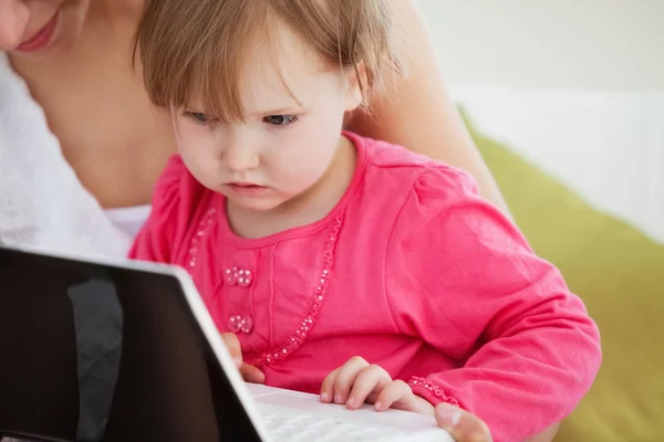 Närbild av en fascinerad flicka med en bärbar dator med sin mor — Stockfoto