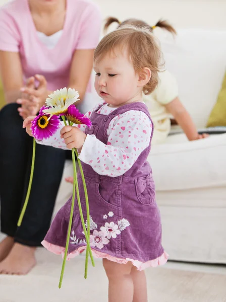 O fetiță adorabilă care ține flori în sufragerie — Fotografie, imagine de stoc