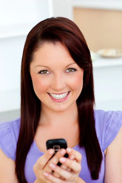 Bright young woman sending a text looking at the camera — Stock Photo, Image