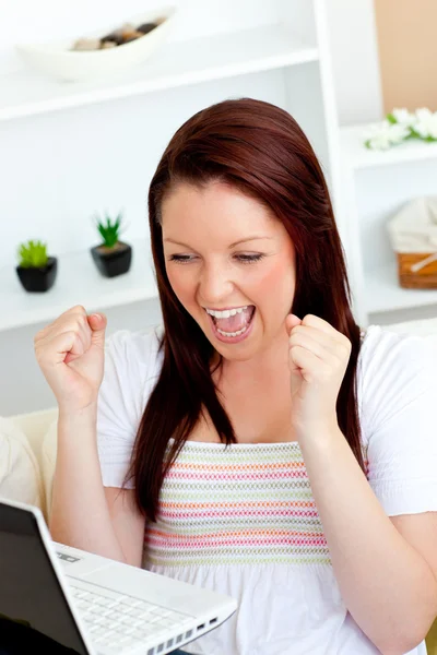 Enthusiastic woman looking at her laptop with arms up — Stock Photo, Image