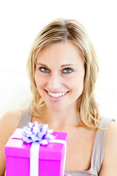 Mujer sonriente sosteniendo un regalo mirando a la cámara — Foto de Stock