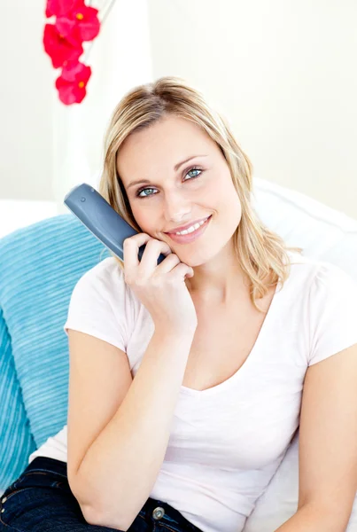 Captivating woman smiling at the camera holding a remote — Stock Photo, Image
