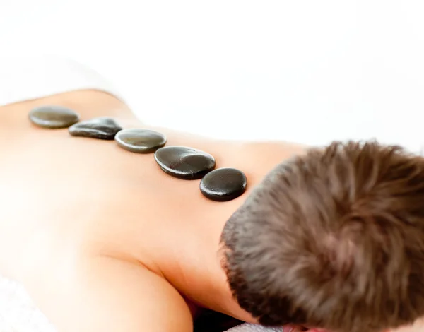 Young caucasian relaxing man with hot stone on his back — Stock Photo, Image