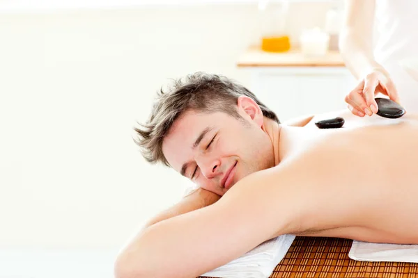 Joven sonriente disfrutando de un masaje de espalda con piedra caliente —  Fotos de Stock