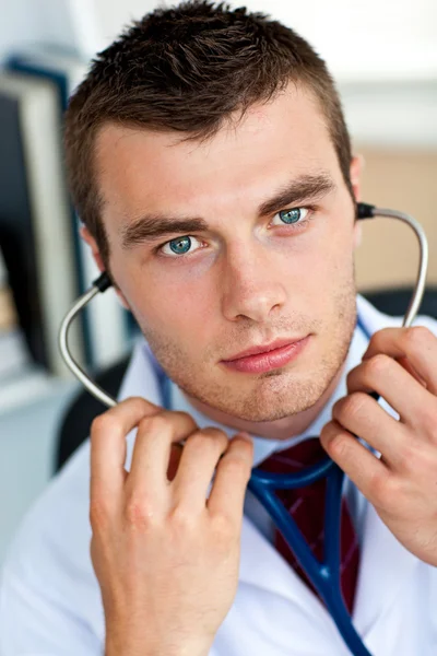 在他的办公室拿听诊器的自信男医生 — 图库照片