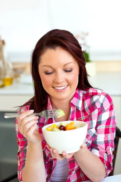 Mujer feliz comiendo una ensalada de frutas para el desayuno en la cocina — Foto de Stock