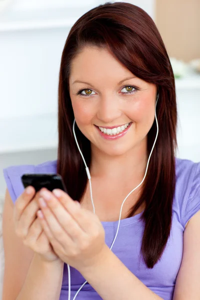 Šťastná žena pomocí její mobil k poslechu hudby se sluchátkem — Stock fotografie