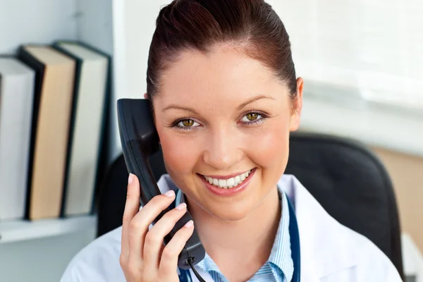 Lachende vrouwelijke arts bellen in haar kantoor — Stockfoto