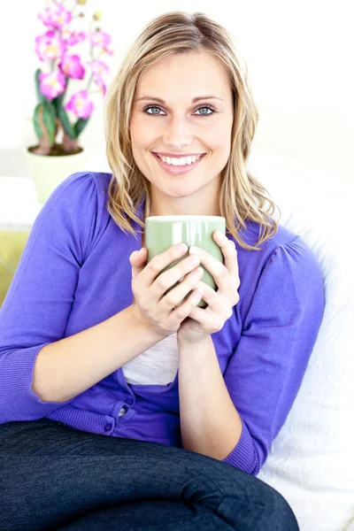 Kaukaski blond kobieta korzystających z jej kawy siedząc na kanapie — Zdjęcie stockowe