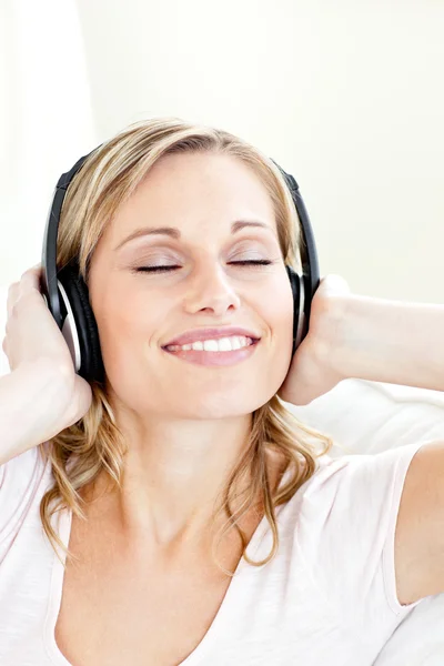 Mujer joven radiante escuchando música usando auriculares — Foto de Stock