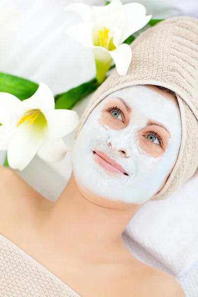 Mooie vrouw met crème op haar gezicht in een spa — Stockfoto